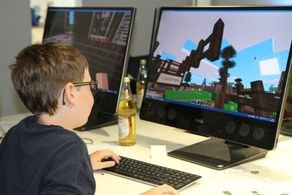 Ein Kind sitzt am PC und programmiert ein Minetest Level