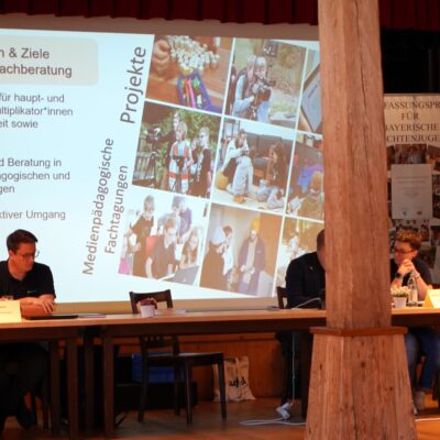 Matthias Penzenstadler berichtet über die Arbeiten der Medienfachberatung vor einer Leinwand