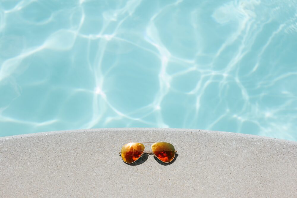 Sonnenbrille am Rand eines Pools